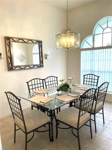 Dining room with a high ceiling, light tile patterned floors, and a notable chandelier