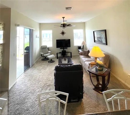 Living room with carpet and ceiling fan and sliders to the lanai