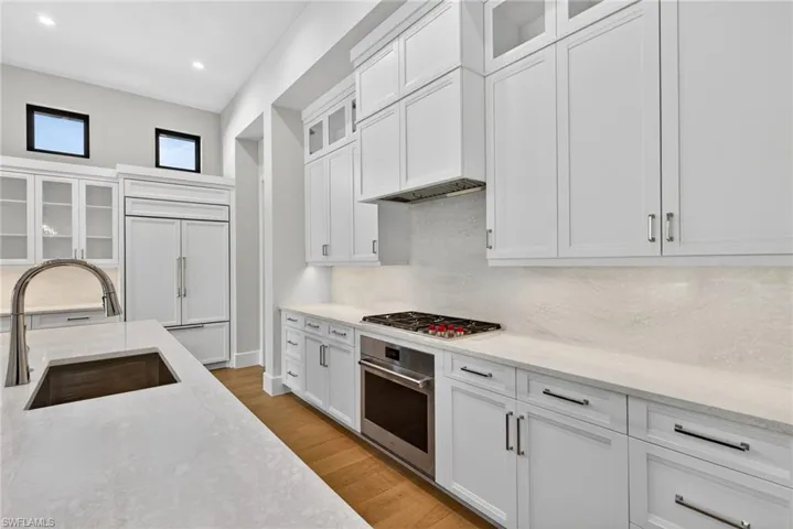 Kitchen with glass fronted cabinets, white cabinetry, stainless steel appliances, and recessed lighting