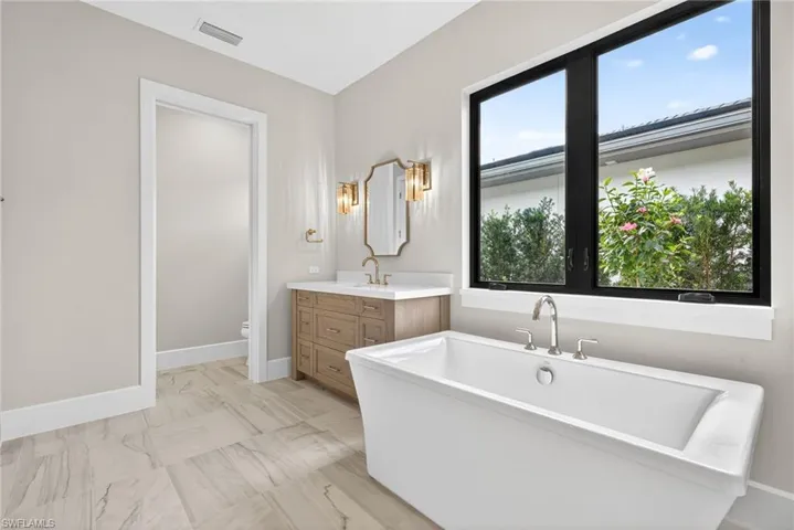 Bathroom with a soaking tub, vanity, and light marble finish floors