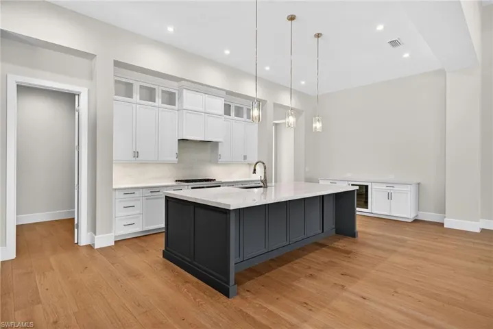 Kitchen with glass insert cabinets, white custom cabinets, elegant and simple hanging light fixtures, large kitchen breakfast bar