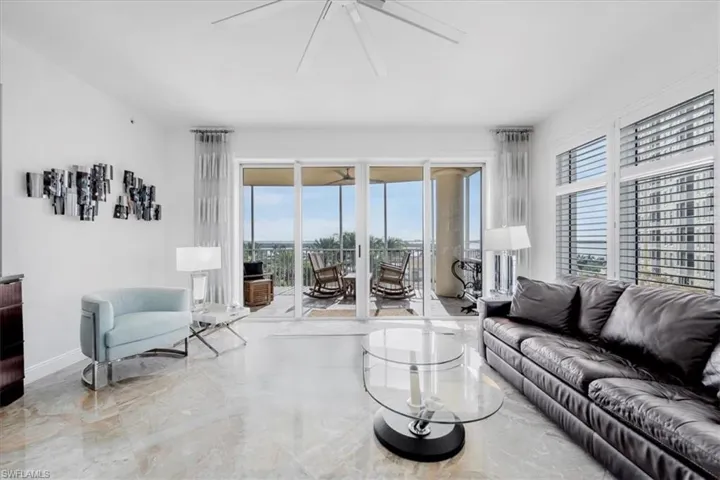 Living room with light marble finish flooring, ceiling fan, and plenty of natural light