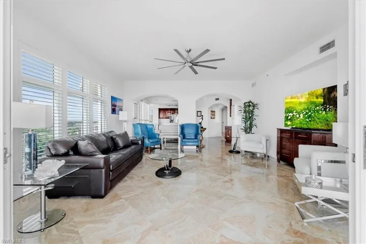 Living room with arched walkways and light marble finish floors