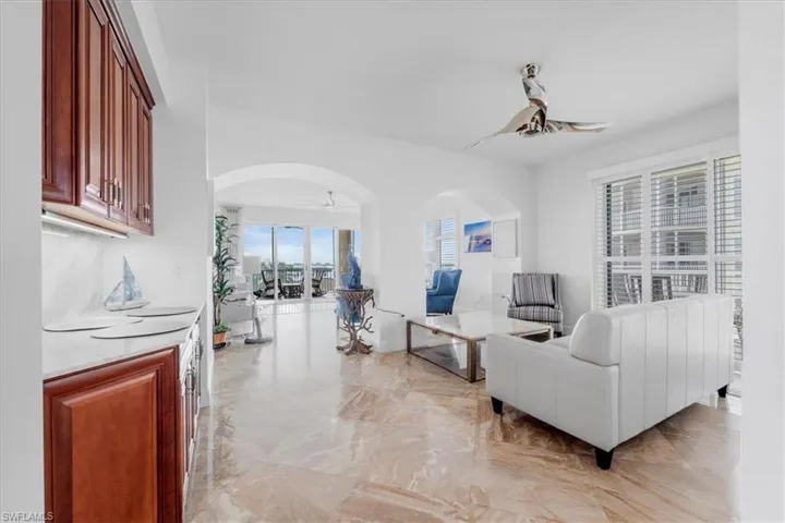Living area with arched walkways, a ceiling fan, and light marble finish flooring