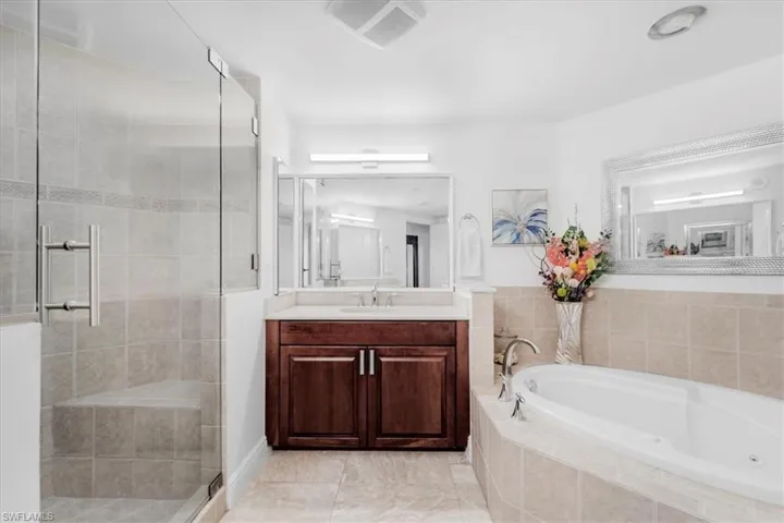 Bathroom featuring a garden tub, vanity, a shower stall, and light tile patterned flooring