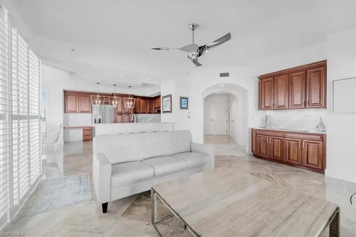 Living area with arched walkways, light marble finish flooring, and a ceiling fan