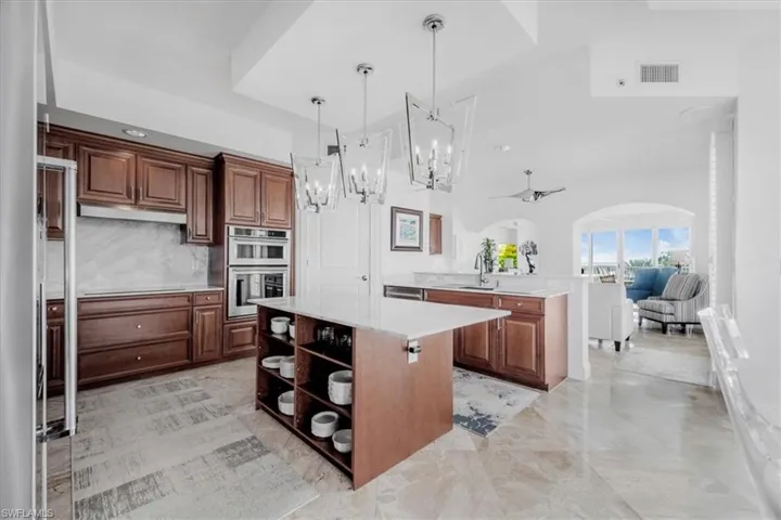 Kitchen with a chandelier, a center island, decorative light fixtures, open shelves, and appliances with stainless steel finishes