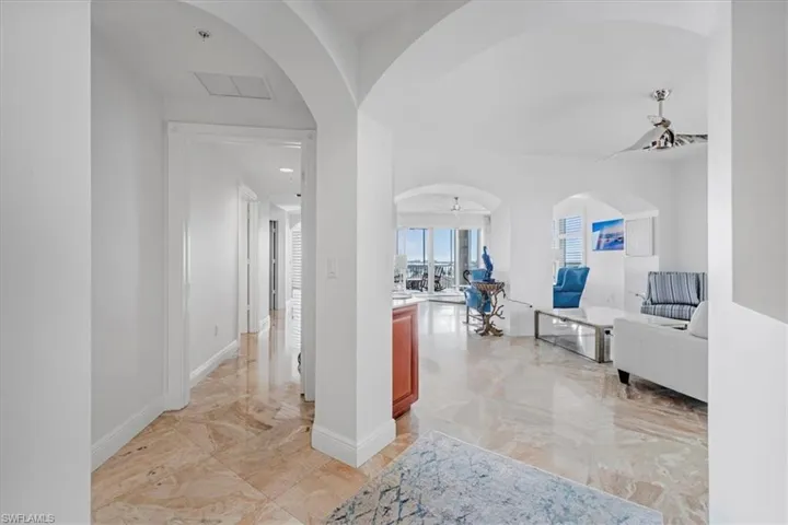 Hallway featuring arched walkways and light marble finish floors