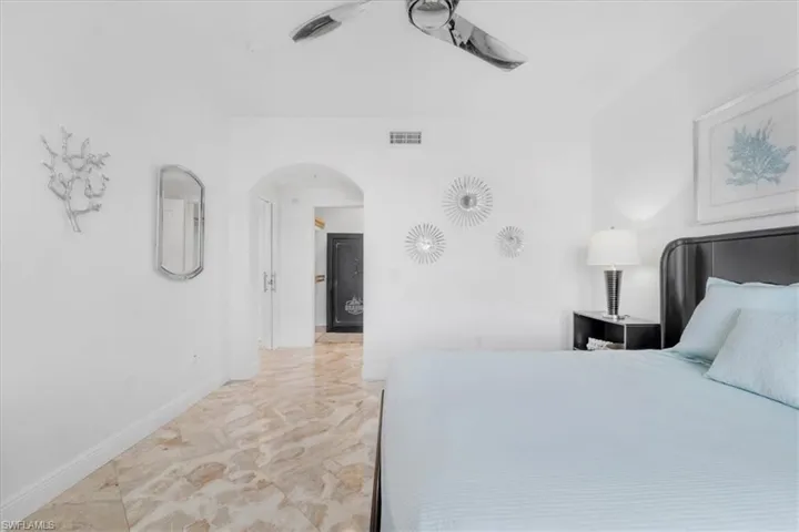 Bedroom with light marble finish flooring, arched walkways, and a ceiling fan