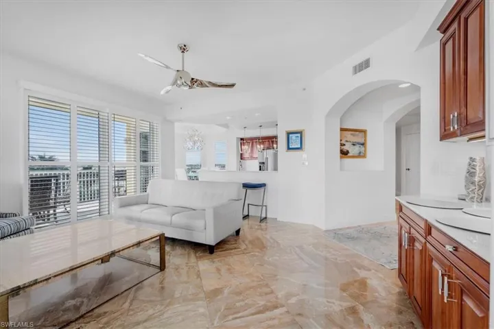 Living area featuring ceiling fan, light marble finish floors, and arched walkways