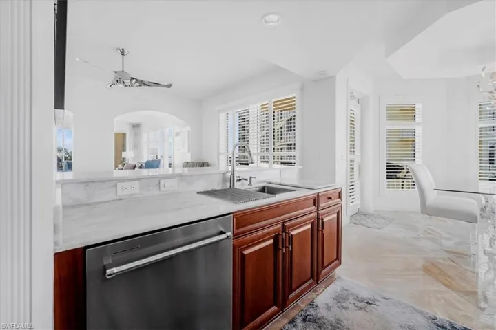 Kitchen featuring dishwasher, healthy amount of natural light, light stone counters, and light marble finish flooring