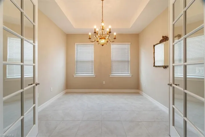 Spare room with french doors, light tile patterned floors, and a tray ceiling