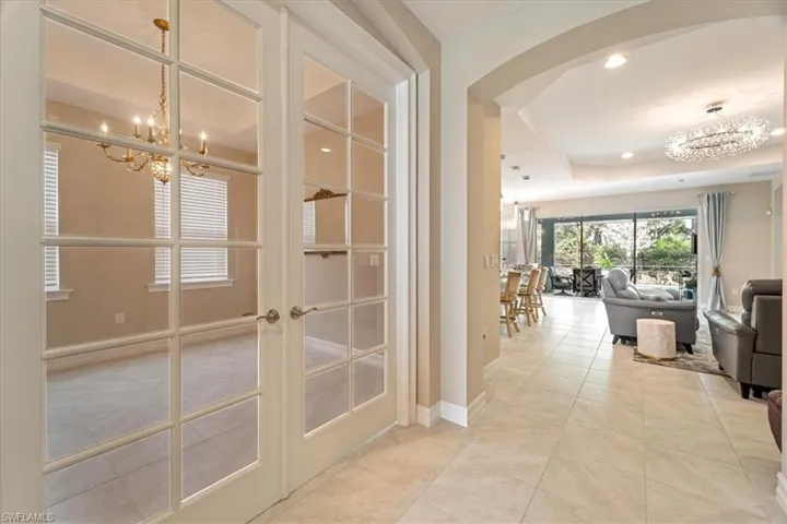 Corridor with an inviting chandelier, french doors, a tray ceiling, and light tile patterned floors