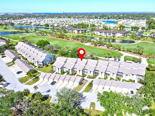 Aerial view of property and surrounding area featuring nearby suburban area, a large body of water, and a golf course