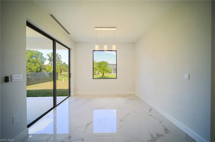 Unfurnished dining area featuring light marble finish flooring and baseboards