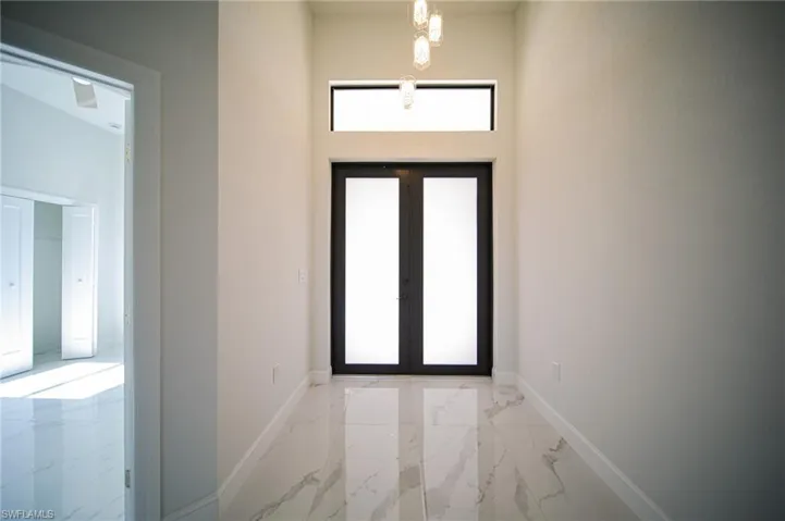 Foyer featuring light marble finish flooring and baseboards