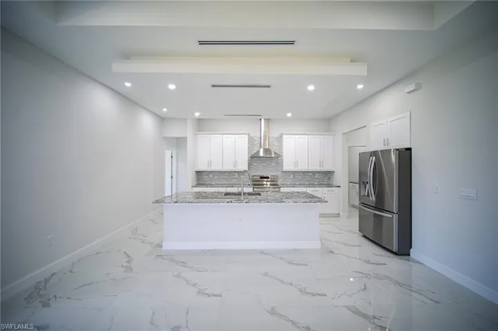 Kitchen featuring light stone counters, appliances with stainless steel finishes, white cabinetry, tasteful backsplash, and recessed lighting