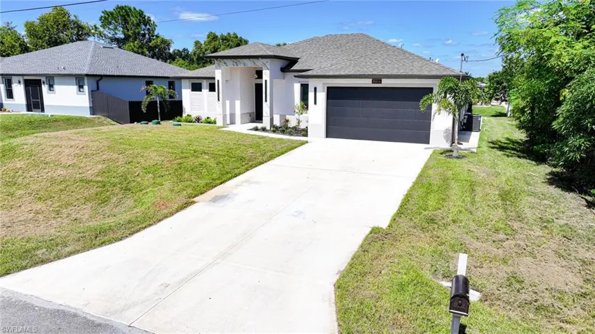 View of front of house featuring stucco siding, driveway, a front yard, a shingled roof, and a garage