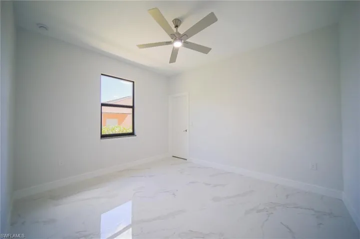 Spare room featuring light marble finish flooring and ceiling fan
