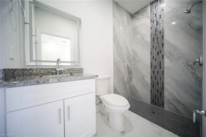 Full bath with a marble finish shower and vanity