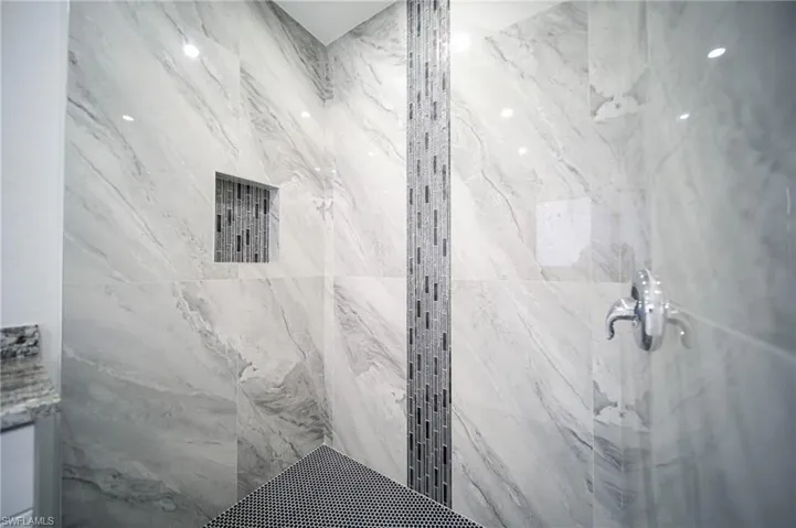 Full bathroom featuring a marble finish shower and vanity