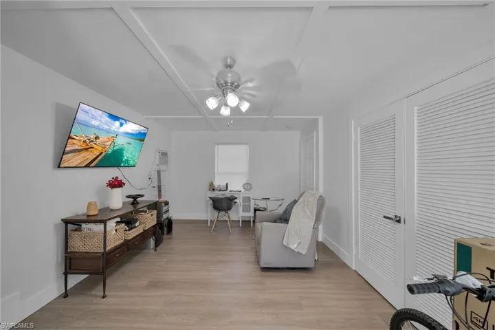 Spacious room featuring light wood-finish flooring, white walls, and a ceiling fan with integrated lighting