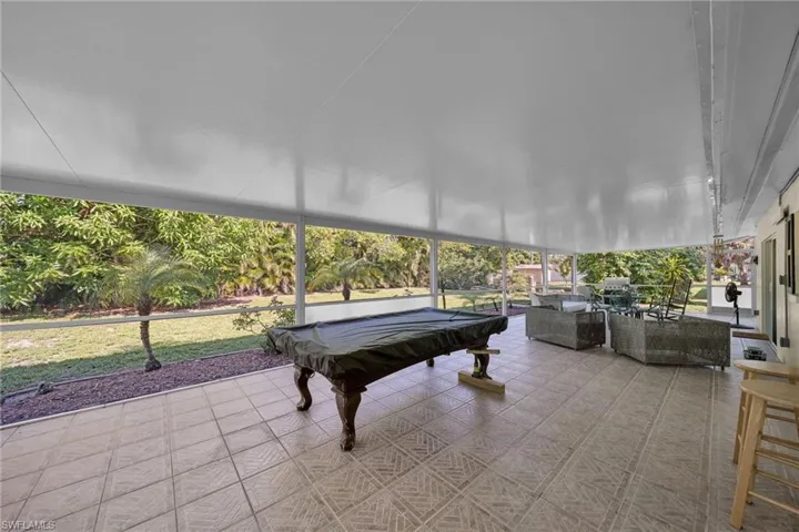 Expansive screened lanai featuring patterned tile flooring and an overhead white panel ceiling