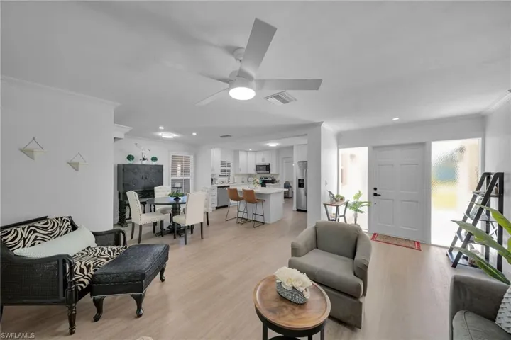 Open-concept living area featuring wood-finish flooring, white walls, and a ceiling fan