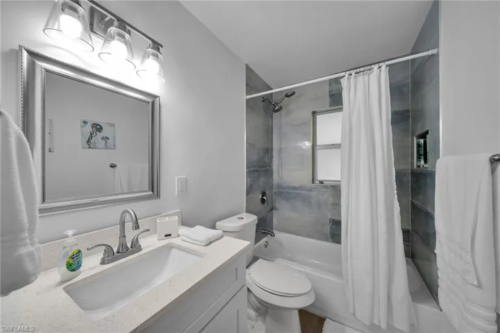 Bathroom featuring a tub/shower combination with tile surround, a built-in shower niche, and a window