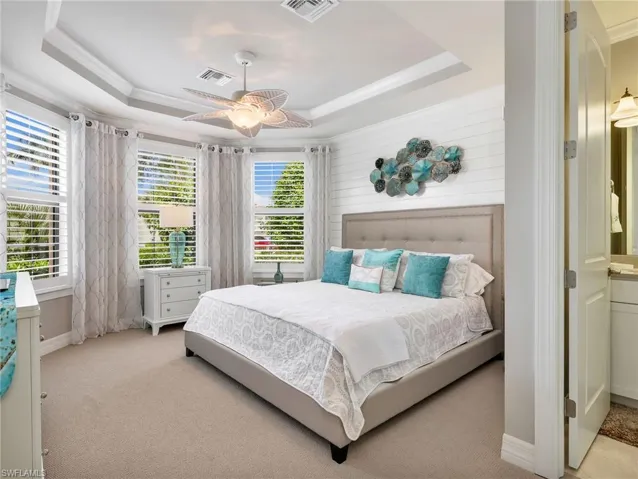 Front Guest Bedroom with Bay Window with Plantation Shutters, Tray Ceiling, Ceiling Fan, Crown Molding, Shiplap Accent Wall, & Custom Curtains