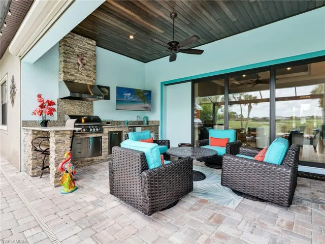 Covered Lanai with Wood Plank Ceiling & Ceiling Fan, Outdoor Stacked Stone Kitchen with Granite Top, Gas Grill, Stainless Steel Beverage Fridge, and Sink