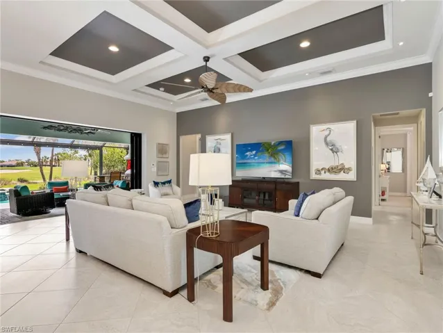 Great Room with Coffered Ceiling and Ceiling Fan with Zero Corner Sliders Leading to the Screened Lanai and Outdoor Kitchen
