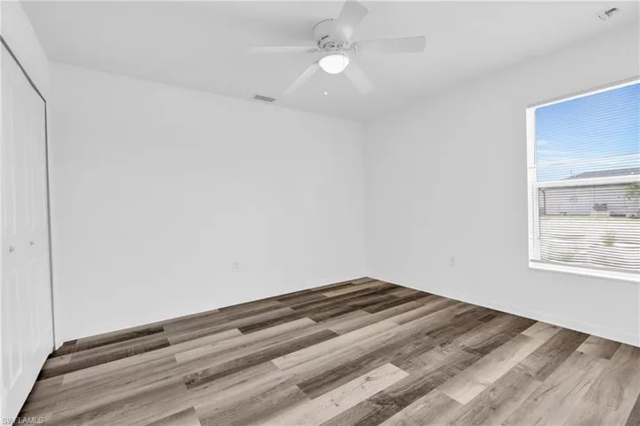 Spare room with visible vents, a ceiling fan, baseboards, and wood finished floors