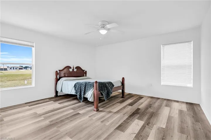 Bedroom with baseboards, a ceiling fan, and light wood-style flooring