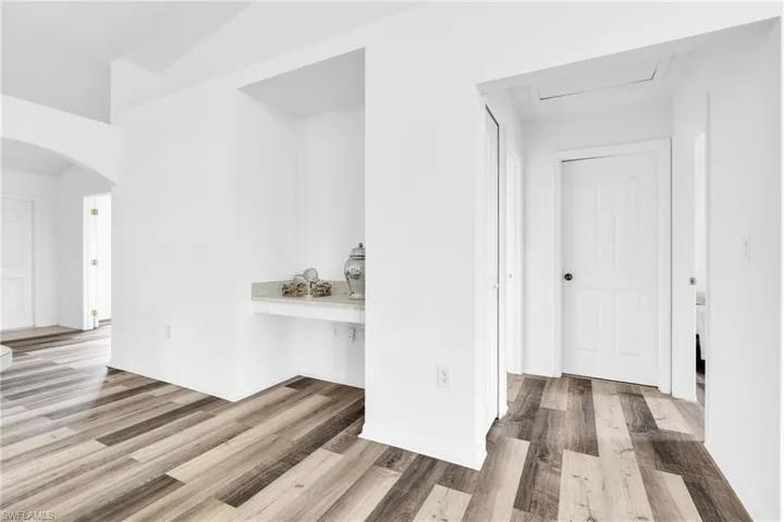 Corridor featuring arched walkways and wood finished floors