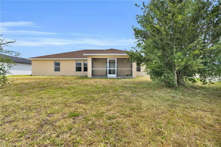 Back of property featuring a sunroom, stucco siding, and a yard