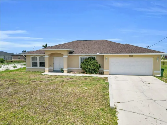 Single story home with a shingled roof, a front lawn, a garage, stucco siding, and driveway