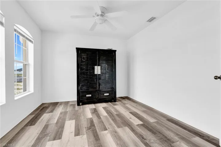 Spare room with ceiling fan, visible vents, and wood finished floors