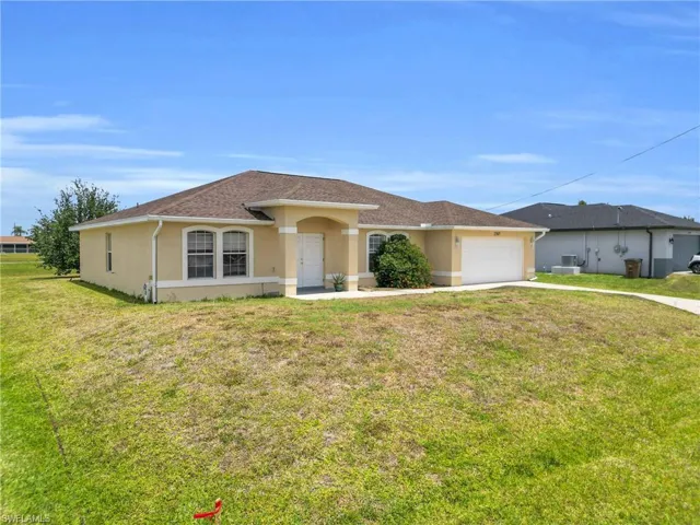 Ranch-style home with a garage, stucco siding, concrete driveway, and a front lawn