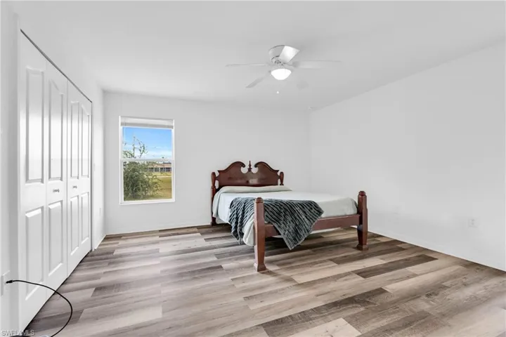 Bedroom featuring baseboards, ceiling fan, a closet, and light wood-type flooring