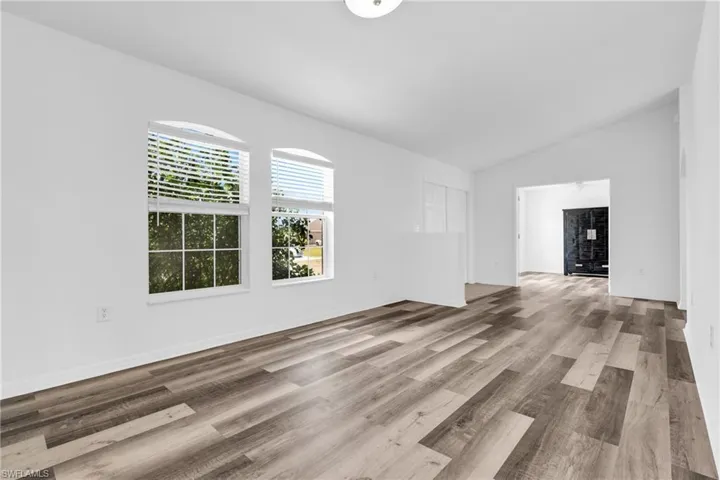 Spare room featuring vaulted ceiling and wood finished floors