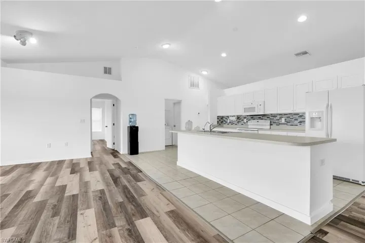 Kitchen featuring light countertops, arched walkways, white appliances, and visible vents