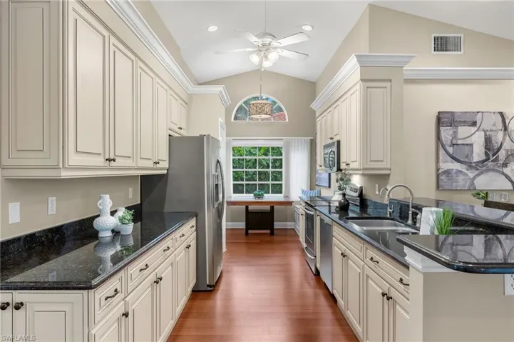 Kitchen with vaulted ceiling, stainless steel appliances, a sink, ceiling fan, and visible vents