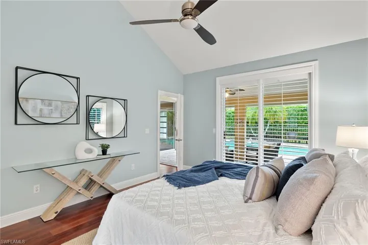 Bedroom featuring high vaulted ceiling, baseboards, access to outside, a ceiling fan, and wood finished floors