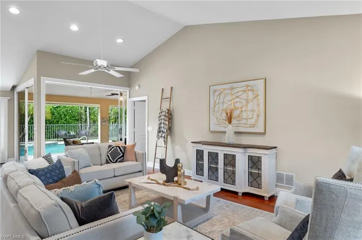 Living area featuring lofted ceiling, recessed lighting, baseboards, a ceiling fan, and wood finished floors