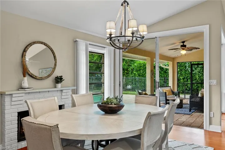 Dining area featuring ceiling fan with notable chandelier, vaulted ceiling, and wood finished floors