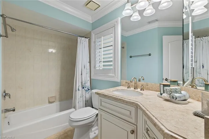 Bathroom with visible vents, crown molding, toilet, vanity, and shower / bathtub combination with curtain