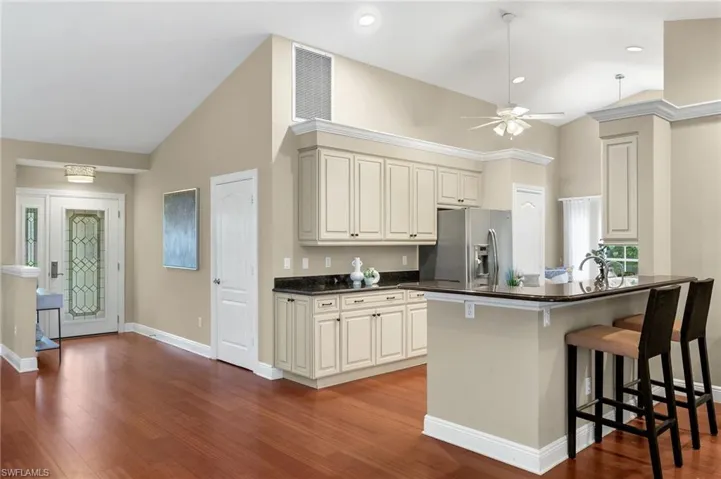 Kitchen featuring stainless steel fridge, dark countertops, ceiling fan, visible vents, and wood finished floors