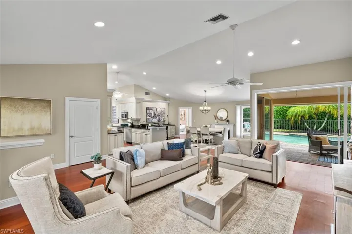 Living area featuring vaulted ceiling, light wood finished floors, ceiling fan with notable chandelier, visible vents, and recessed lighting