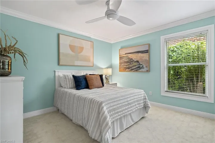 Bedroom featuring baseboards, crown molding, and light colored carpet